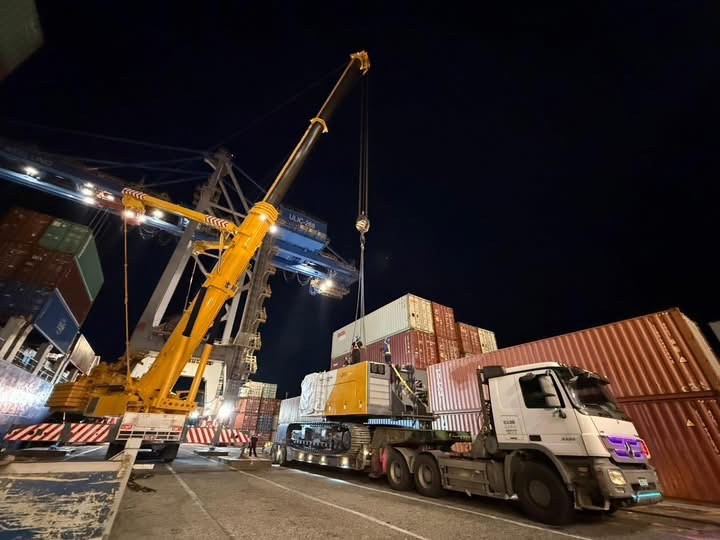 Truck and mobile crane handling containers at night